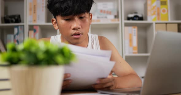 Tired man using laptop and looking document