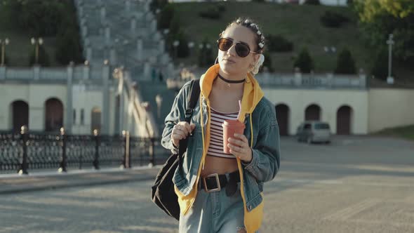 Young Woman with Braids Walking in City Streets at Sunset