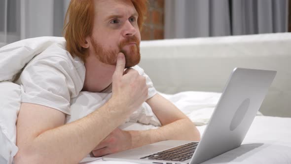 Thinking Man Working on Laptop Lying in Bed