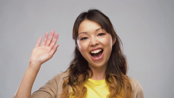 Smiling Asian Woman Waving Hand