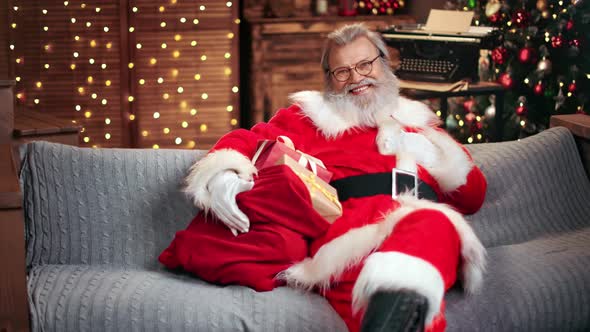 Gray Haired Man in Santa Claus Costume Posing with Sack Full of Presents