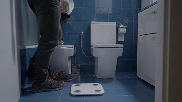 Man Weighting Himself in the Bathroom Without Shoes  Close Up Shot