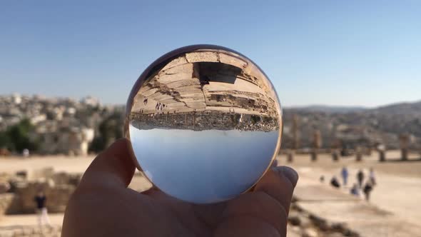 Crystal Ball Reflection Against Ancient Ruins of Roman City, Columns, Hand Holding