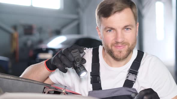 The Car Mechanic Shines a Flashlight Into the Camera Lens