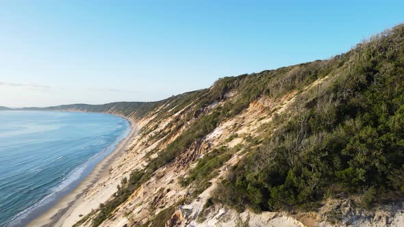 Revealing drone view of the constantly re-sculpt cliff lines of coloured sands at Rainbow Beach Quee