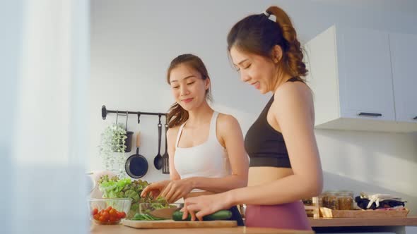 Asian young two women friend playing while cooking salad in kitchen.