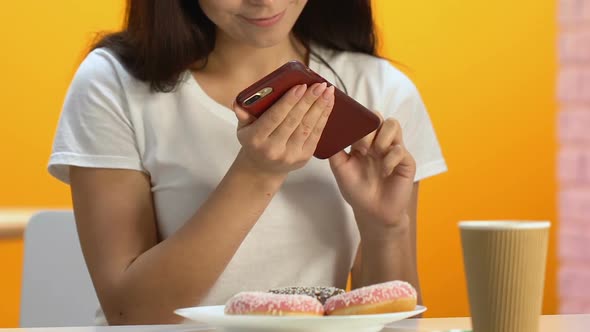 Happy Girl Taking Photo of Appetizing Doughnuts on Cellphone, High Calorie Meal