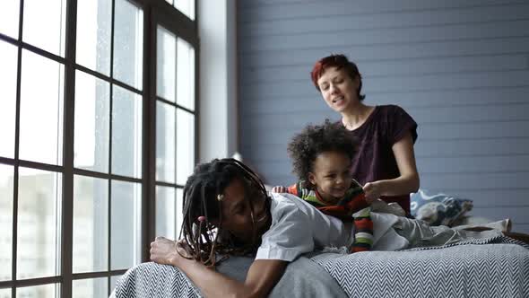 Happy Mixed Family Playing with Son in the Bedroom