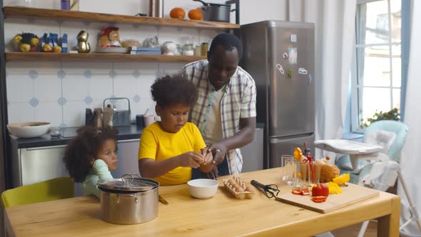 Happy African Father with Children Cooking on Paternity Leave in Kitchen