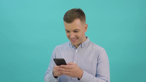 Caucasian Middleaged Man in a Blue Shirt is Corresponding on a Smartphone