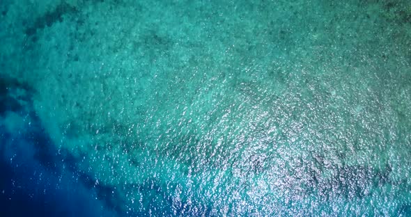 Wide fly over tourism shot of a sandy white paradise beach and aqua blue ocean background in colorfu