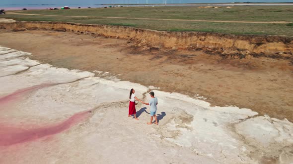 Lovely Young Couple Walking Along Beautiful Pink Lake with Salty Shore