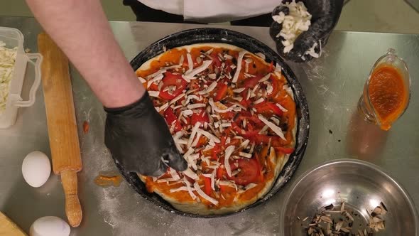Close-up of the Chef Sprinkling Freshly Baked Pizza with Cheese in the Kitchen.