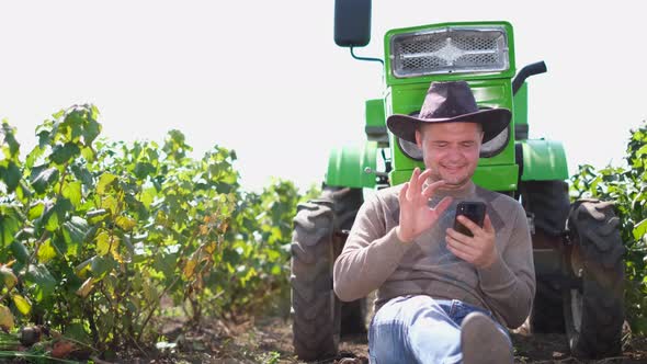 A Modern Farmer or Winemaker Talks on a Smartphone During the Harvest Season in the Vineyard