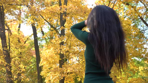 A Young Asian Woman Fixes Her Hair in A Park