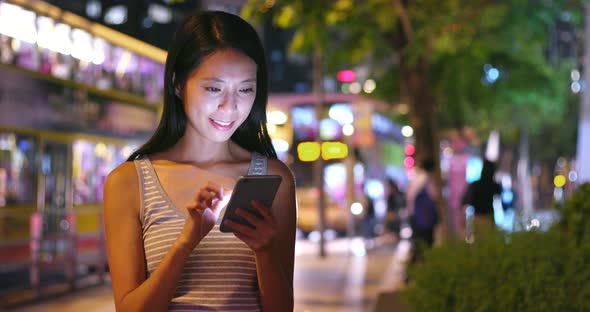 Woman using mobile phone in city at night 