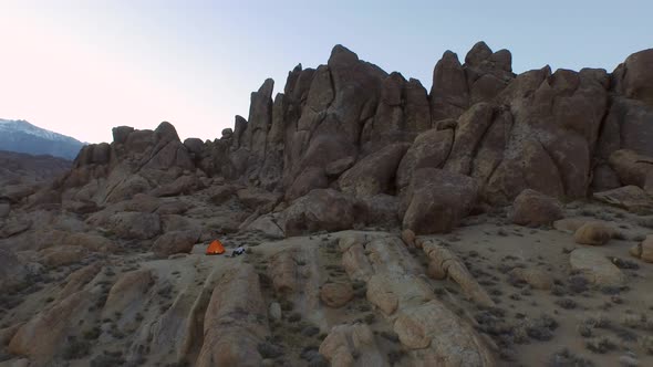 Aerial shot of a young man backpacker camping with his dog in a mountainous desert.