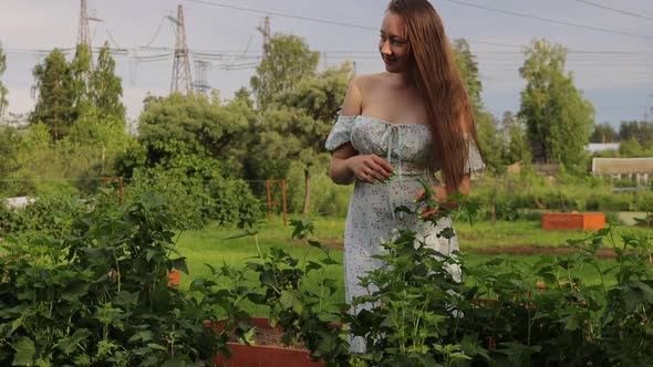 Woman Touching Tree Branches in Garden