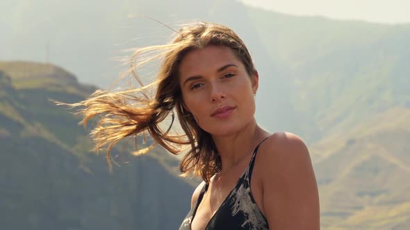 Pretty Model Smiling as Wind Blows Her Hair With Mountain in the Background