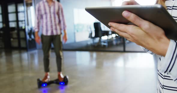 Man on hoverboard using digital tablet with colleagues