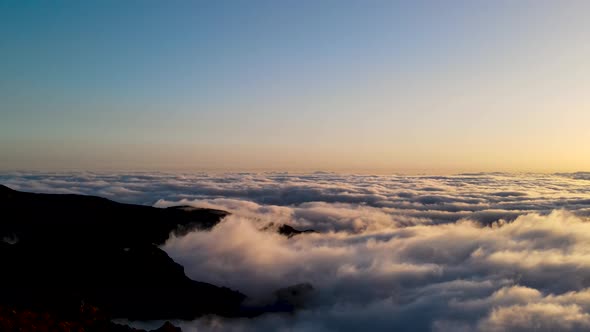 People standing on a mountain peak above clouds and watching the sunset in Pico do Arieiro, Madeira,