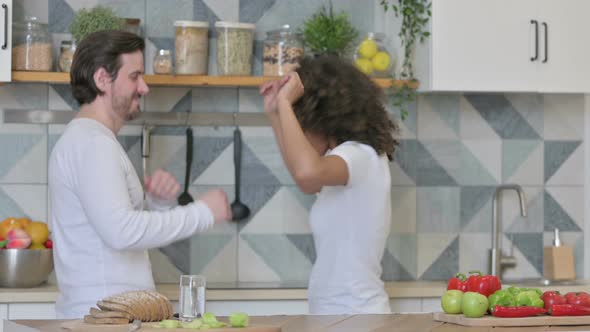 Happy Mixed Race Couple Dancing in Kitchen