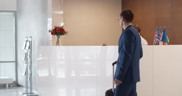 Man with Suitcase in Hotel Check Out at Reception or Front Office