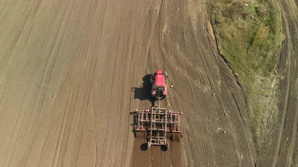 Modern Red Tractor With A Chisel Cultivator Prepares Fertile Soil For Sowing On A Sunny Day