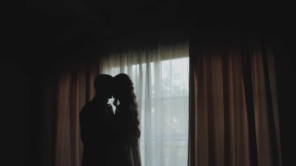 Silhouette of a Man and Woman in Love Hugging By the Window