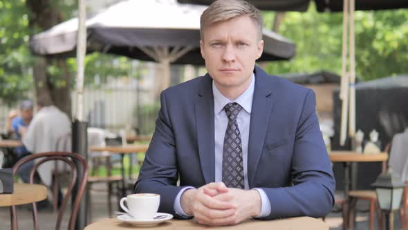 Serious Businessman Sitting in Outdoor Cafe