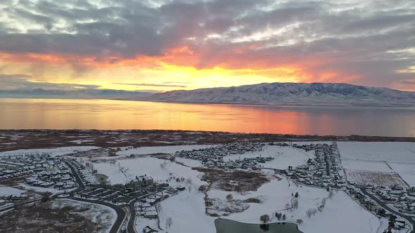 Aerial view flying over snow covered urban city landscape at sunset