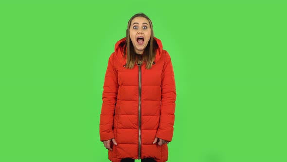 Lovely Girl in a Red Down Jacket with Shocked Surprised Wow Face Expression . Green Screen