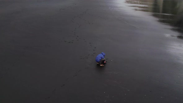 Drone Of Photographer Crouching On Black Beach