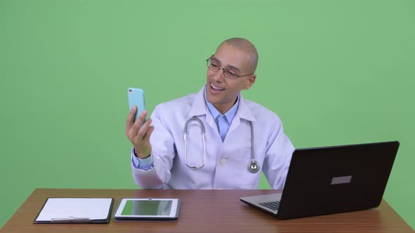 Happy Bald Multi Ethnic Man Doctor Video Calling at Work