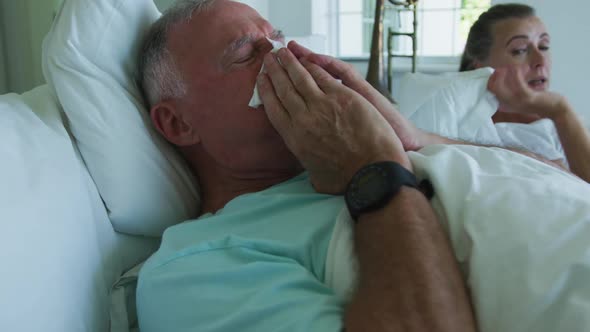 Sick caucasian senior man coughing while lying in the bed at home