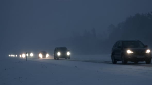 Cars Driving on Snow Covered Road in Winter Blizzard Snowstorm