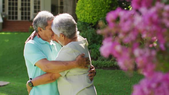 Video of happy biracial senior couple embracing in garden
