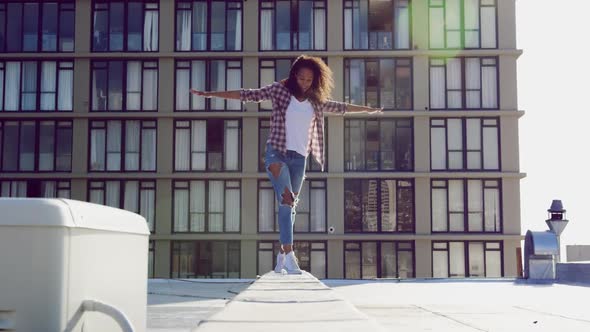 Fashionable young woman on urban rooftop balancing