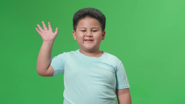 The Happy Asian Little Boy Waving Hand And Say Bye Bye While Standing On Green Screen In The Studio