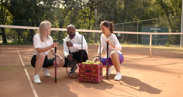 Three Multi Racial Tennis Players Talking on Court