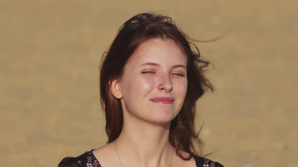 Young Smiling Woman in Black Dress on the Beach