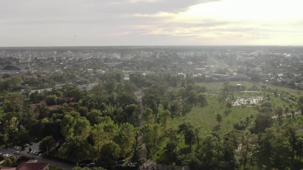 White birds fly over small city in the plains at sunset