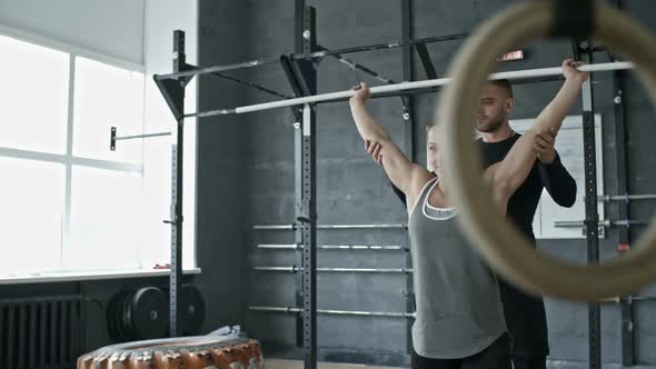 Personal Coach Helping Woman Doing Squats with Barbell