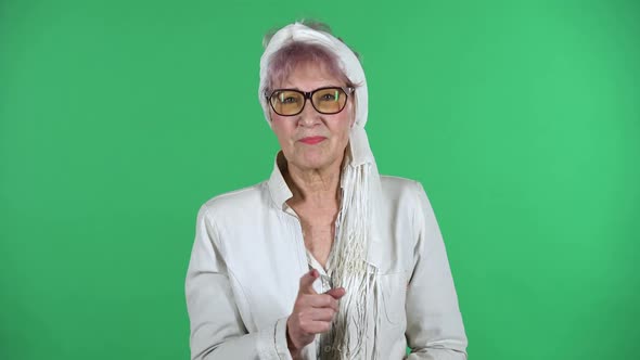 Portrait of Old Stylish Woman Is Scolding, Shaking Her Index Finger Isolated Over Green Background.