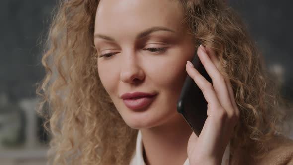 Handheld Close Up of a Young Adult Curly Caucasian Woman on a Phone Call Indoors