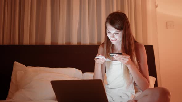 Happy Young Woman Holding Credit Card Using Instant Mobile Payments at Home