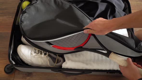 Tennis player puts his racket in the travel luggage