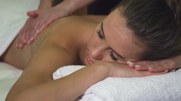 Cropped Shot of the Face and Back of a Girl Who Has a Back Massage in the Spa Salon