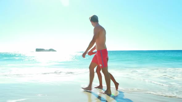 Couple holding hands while walking on the beach