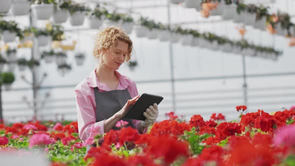 Portrait Girl of a Greenhouse Worker Caring for Saplings of Beautiful Red Flowers and Writing Text